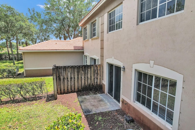 rear view of house featuring fence, a tile roof, and stucco siding
