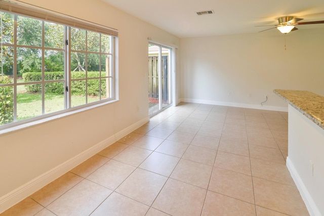 empty room featuring visible vents, baseboards, ceiling fan, and light tile patterned floors