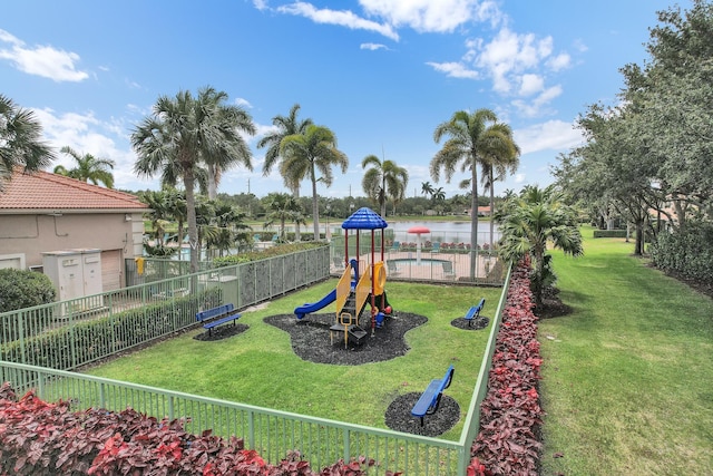 view of playground with a community pool, fence, a water view, and a yard