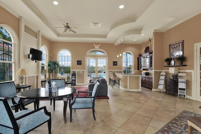 dining area with ceiling fan, a wealth of natural light, ornamental molding, and a raised ceiling