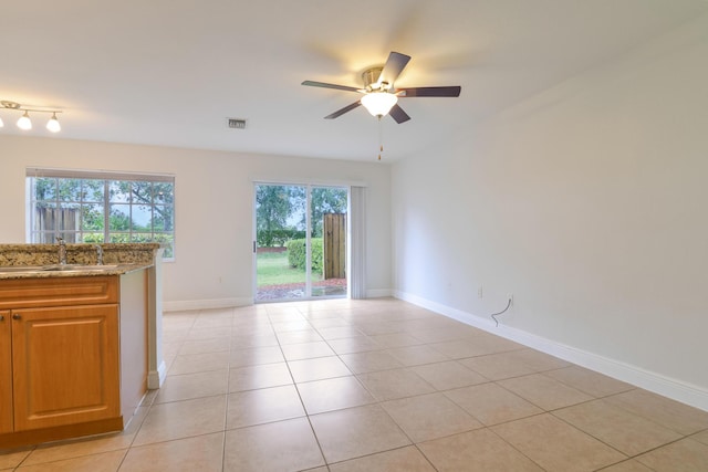 spare room with visible vents, a ceiling fan, light tile patterned floors, a sink, and baseboards