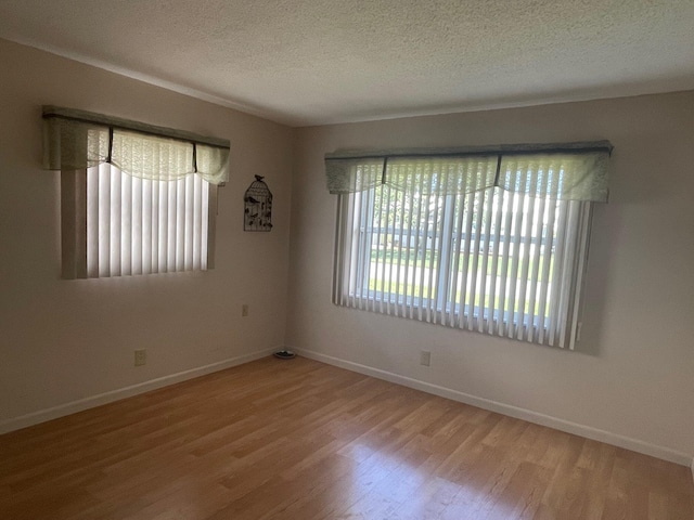 unfurnished room with baseboards, wood finished floors, and a textured ceiling