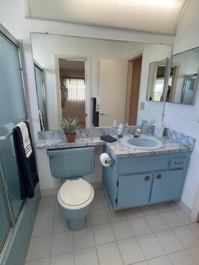 bathroom with toilet, combined bath / shower with glass door, vanity, and tile patterned flooring