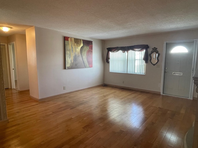 unfurnished room featuring a textured ceiling, wood finished floors, and baseboards