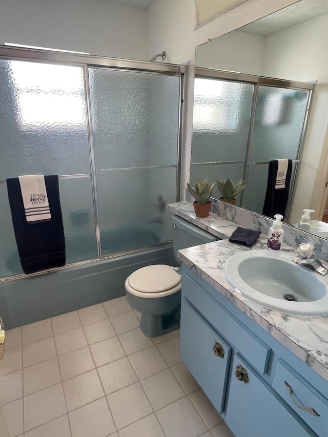 bathroom featuring tile patterned floors, bath / shower combo with glass door, toilet, and vanity