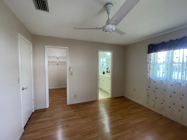 unfurnished bedroom with a textured ceiling, wood finished floors, and multiple windows