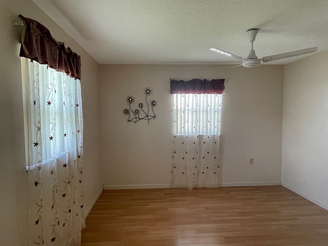 unfurnished room featuring light wood finished floors, a textured ceiling, ceiling fan, and baseboards