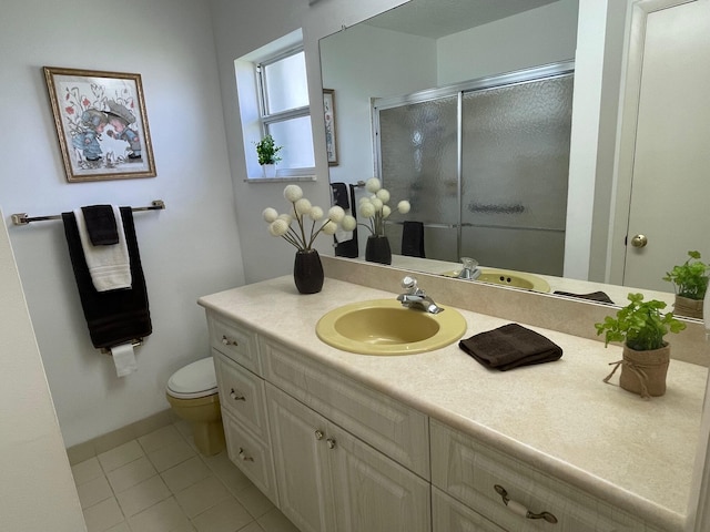 bathroom with tile patterned floors, a shower with shower door, vanity, and toilet