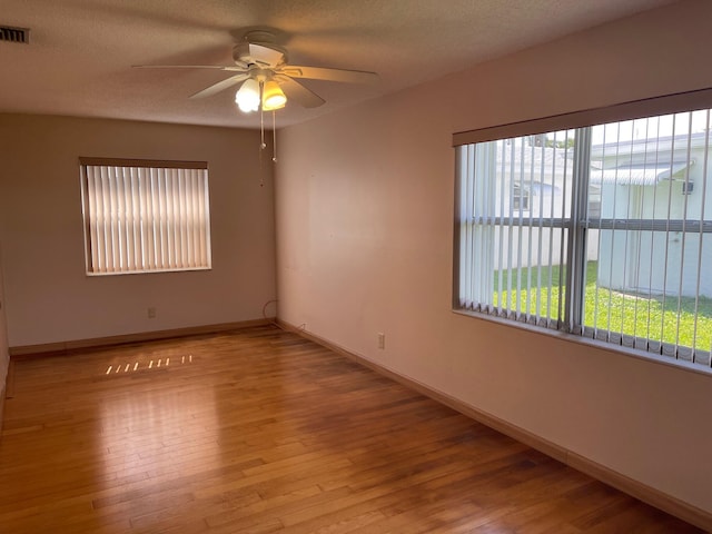 unfurnished room with baseboards, visible vents, wood finished floors, and a ceiling fan