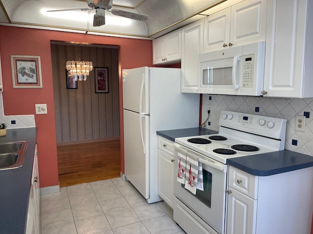 kitchen featuring dark countertops, white appliances, and white cabinetry