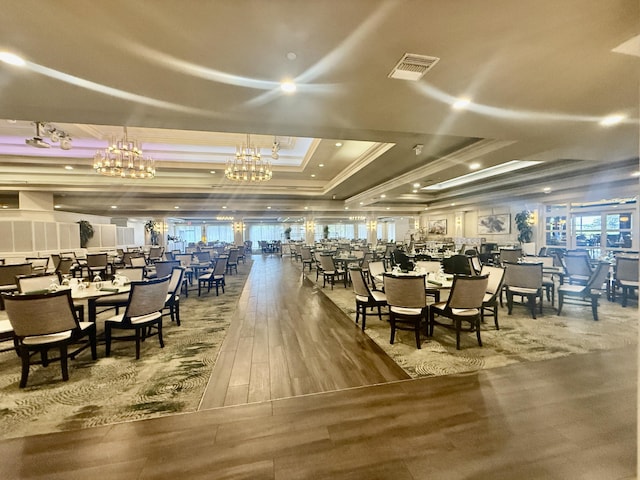 dining space featuring crown molding, a tray ceiling, visible vents, and wood finished floors
