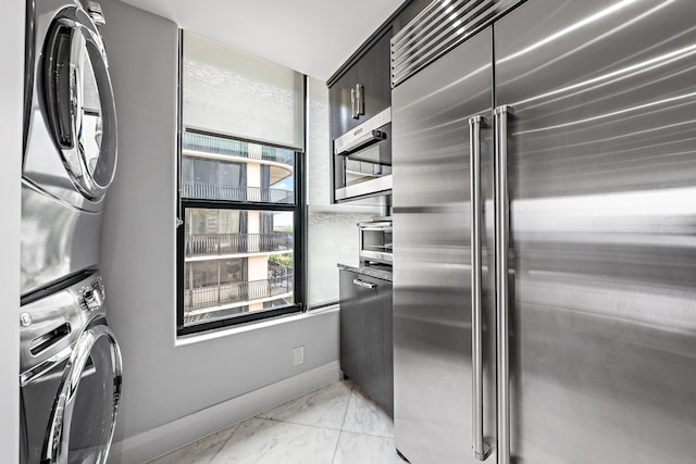 3610 S Ocean Blvd Unit 405, South Palm Beach, FL 33480 - kitchen with stainless steel appliances, stacked washer / drying machine, light marble finish floors, and baseboards