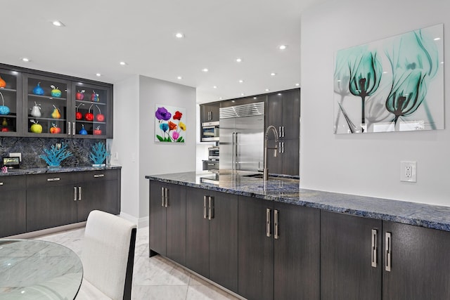 3610 S Ocean Blvd Unit 405, South Palm Beach, FL 33480 - kitchen featuring built in refrigerator, a sink, dark stone counters, tasteful backsplash, and glass insert cabinets