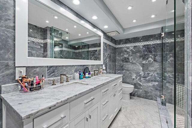 3610 S Ocean Blvd Unit 405, South Palm Beach, FL 33480 - bathroom featuring tile walls, a stall shower, toilet, double vanity, and marble look tile flooring