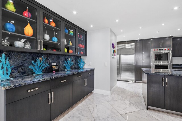 3610 S Ocean Blvd Unit 405, South Palm Beach, FL 33480 - kitchen with stainless steel appliances, baseboards, light marble finish floors, tasteful backsplash, and dark stone countertops