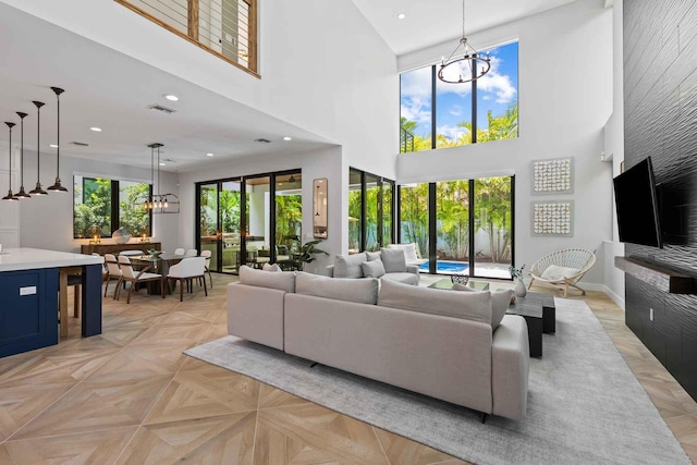 living area featuring recessed lighting, a high ceiling, a notable chandelier, and visible vents