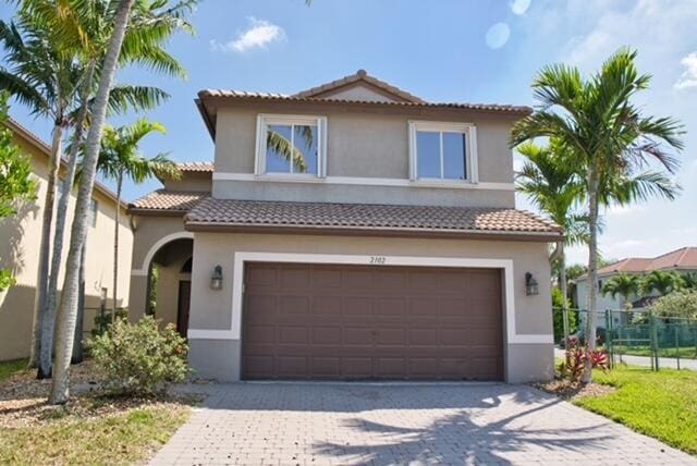 2102 Little Torch St, Riviera Beach, FL 33407 - mediterranean / spanish-style house featuring a tile roof, a garage, decorative driveway, fence, and stucco siding