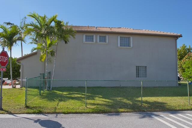 2102 Little Torch St, Riviera Beach, FL 33407 - view of property exterior with fence, a lawn, and a tile roof