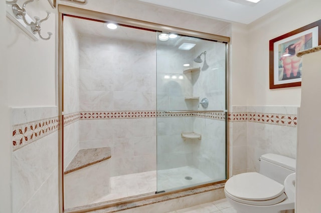 3420 S Ocean Blvd Unit 3W, Highland Beach, FL 33487 - bathroom with a tile shower, toilet, tile walls, tile patterned floors, and wainscoting