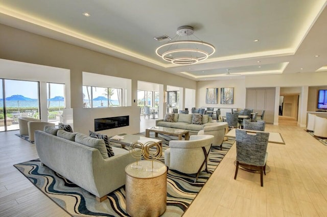3420 S Ocean Blvd Unit 3W, Highland Beach, FL 33487 - living area with a raised ceiling, a chandelier, a glass covered fireplace, light wood-style floors, and a mountain view