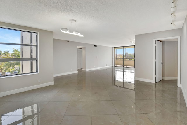 6372 La Costa Dr Unit 302, Boca Raton, FL 33433 - tiled empty room with plenty of natural light, a textured ceiling, baseboards, and rail lighting