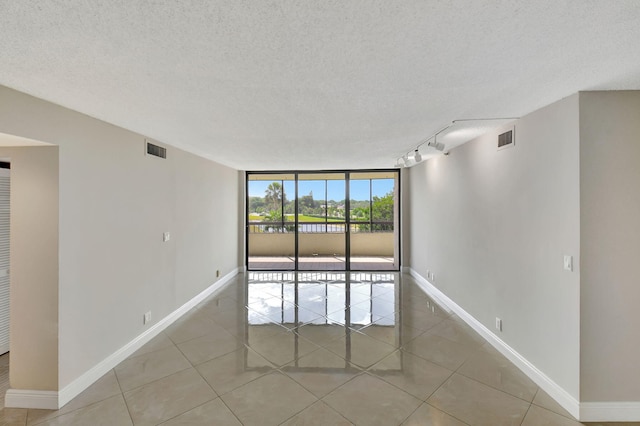 6372 La Costa Dr Unit 302, Boca Raton, FL 33433 - unfurnished room featuring light tile patterned flooring, baseboards, a textured ceiling, floor to ceiling windows, and track lighting