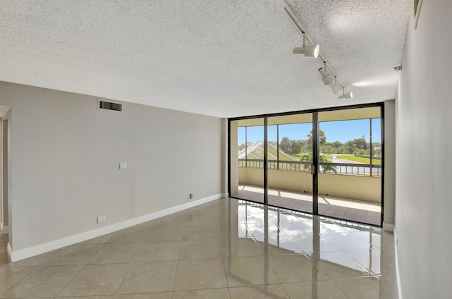 6372 La Costa Dr Unit 302, Boca Raton, FL 33433 - unfurnished room with a textured ceiling, baseboards, a wall of windows, light tile patterned floors, and track lighting