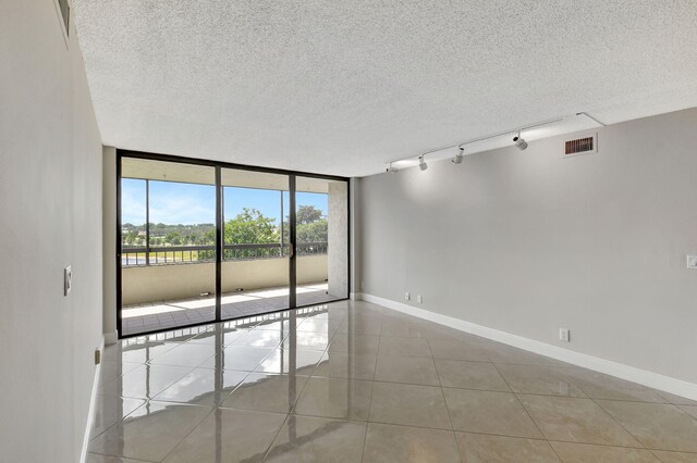6372 La Costa Dr Unit 302, Boca Raton, FL 33433 - empty room featuring expansive windows, tile patterned flooring, a textured ceiling, baseboards, and rail lighting