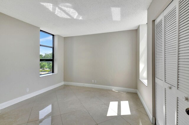 6372 La Costa Dr Unit 302, Boca Raton, FL 33433 - unfurnished bedroom featuring light tile patterned floors, baseboards, a closet, and a textured ceiling