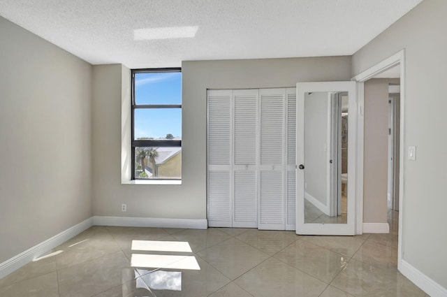 6372 La Costa Dr Unit 302, Boca Raton, FL 33433 - unfurnished bedroom featuring a closet, a textured ceiling, baseboards, and tile patterned floors