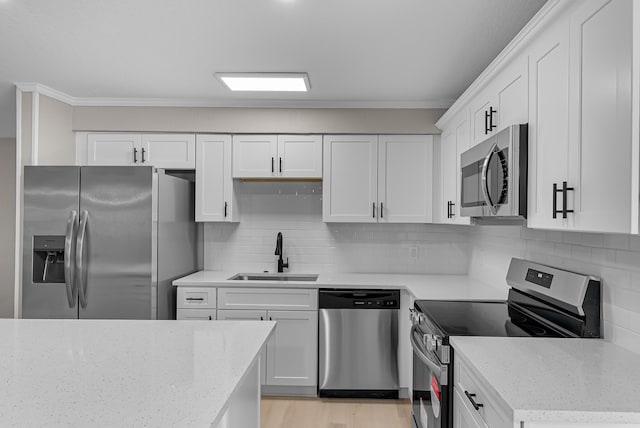 kitchen with appliances with stainless steel finishes, light stone counters, ornamental molding, and a sink