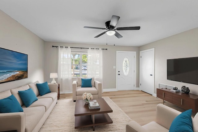 living area with ceiling fan, baseboards, and light wood-type flooring