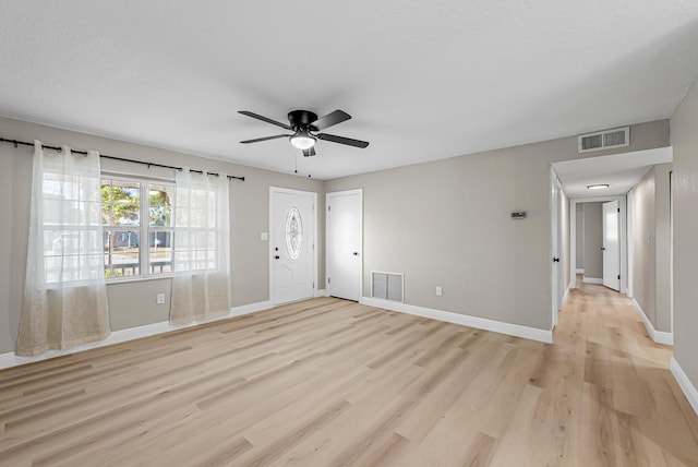 unfurnished living room featuring baseboards, light wood-style flooring, visible vents, and ceiling fan