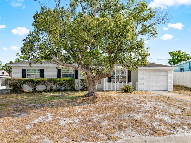 view of front facade with a porch, concrete driveway, an attached garage, and fence