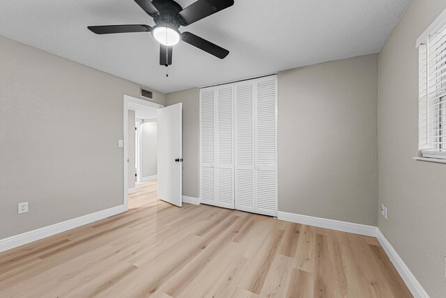 unfurnished bedroom featuring baseboards, visible vents, light wood-style floors, a closet, and ceiling fan