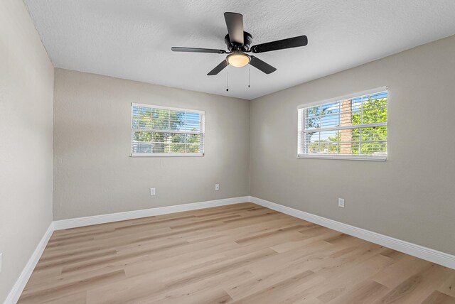 spare room with baseboards, a ceiling fan, a textured ceiling, and light wood finished floors