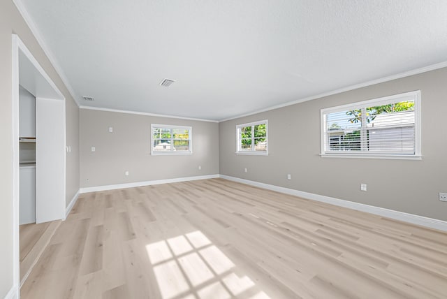 unfurnished living room featuring light wood finished floors, baseboards, visible vents, and crown molding