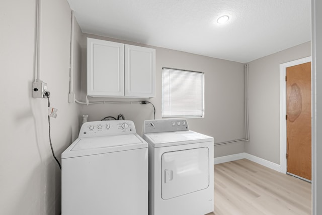 laundry room with a textured ceiling, light wood-type flooring, cabinet space, baseboards, and independent washer and dryer