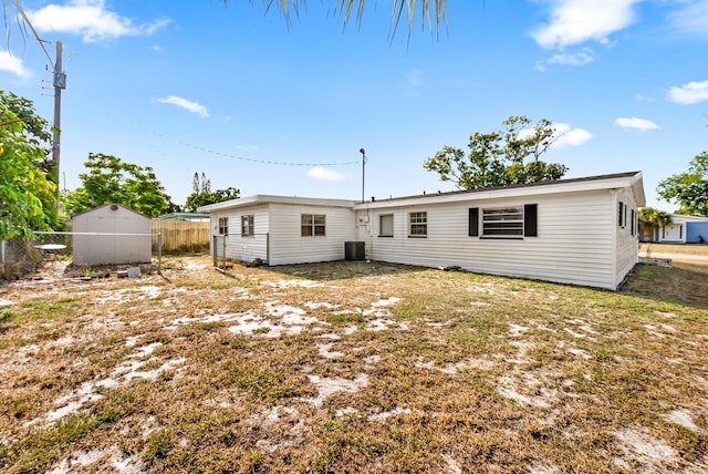 rear view of property with a storage shed, central AC unit, fence, and an outdoor structure