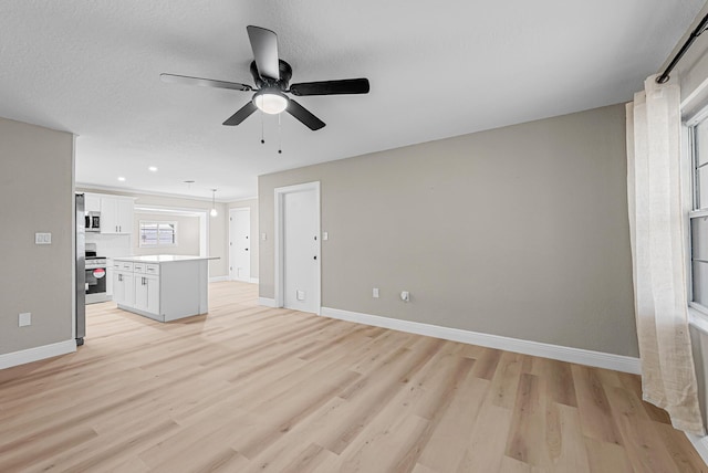 unfurnished living room with baseboards, light wood-type flooring, and ceiling fan