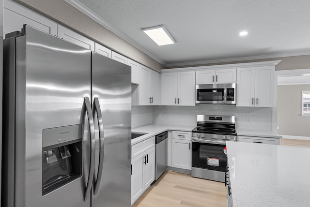 kitchen with ornamental molding, light wood-style floors, appliances with stainless steel finishes, and decorative backsplash