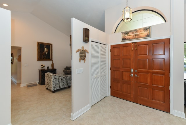 foyer featuring lofted ceiling, baseboards, and light tile patterned floors