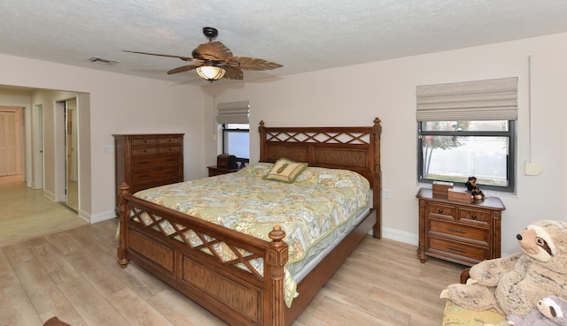bedroom featuring light wood-style floors, ceiling fan, baseboards, and a textured ceiling