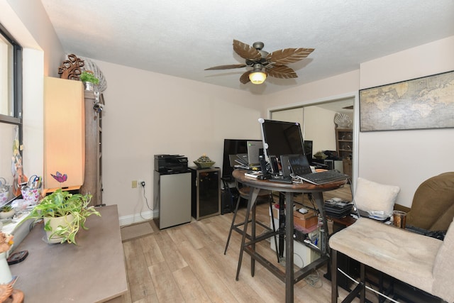 home office featuring ceiling fan, light wood-style floors, a textured ceiling, and baseboards