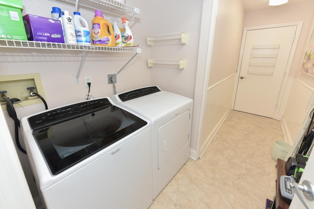 clothes washing area with washer and dryer, light tile patterned floors, and baseboards