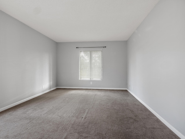 carpeted empty room featuring baseboards