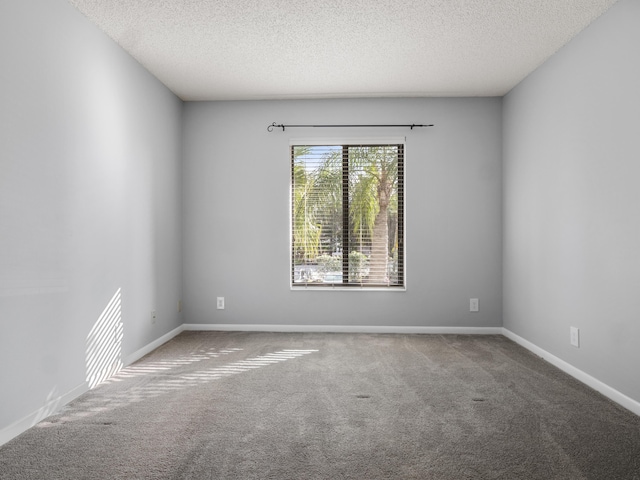 carpeted spare room with a textured ceiling and baseboards