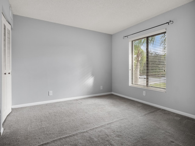 unfurnished room featuring a textured ceiling, carpet flooring, and baseboards