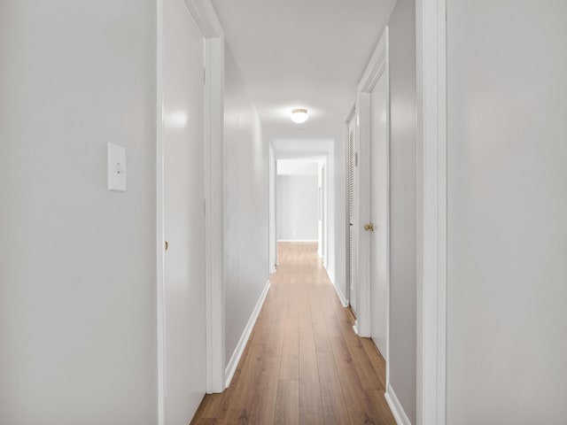 corridor with wood finished floors and baseboards
