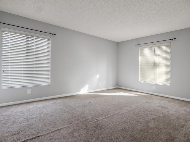 carpeted empty room featuring a textured ceiling and baseboards